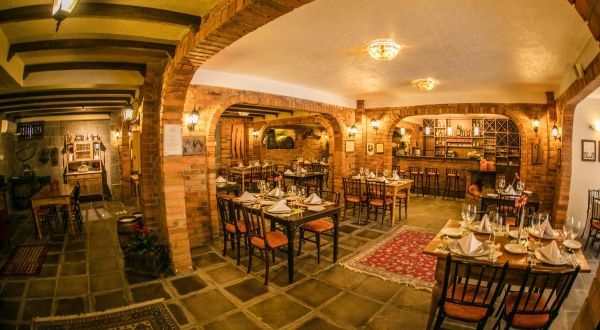 uma grande sala de jantar repleta de mesas e cadeiras em um restaurante.