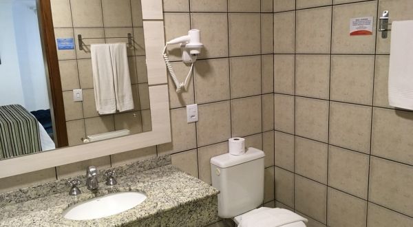 um banheiro com pia, vaso sanitário e espelho.
