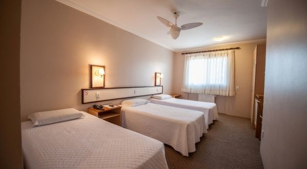 um quarto de hotel com três camas e ventilador de teto.