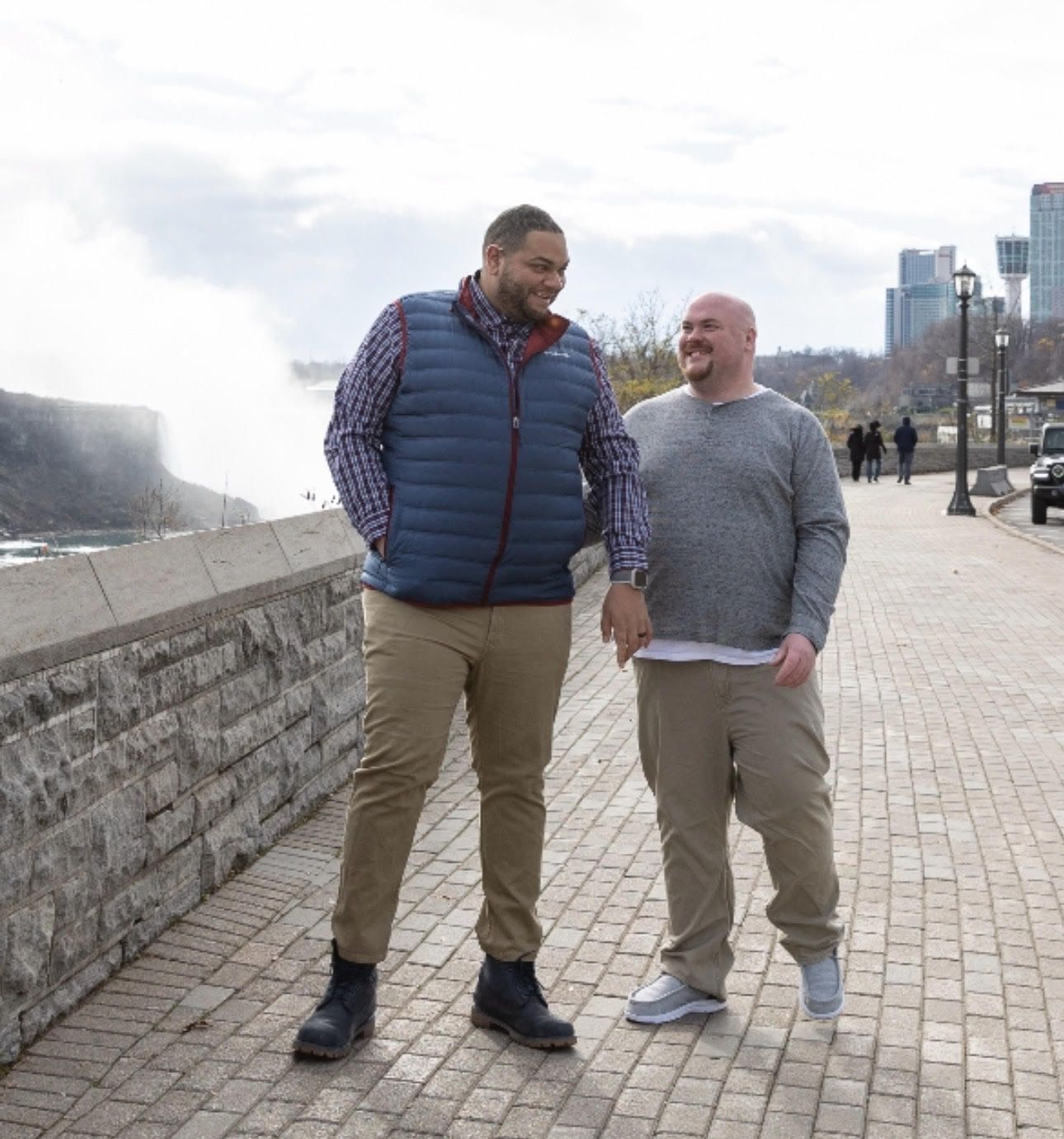 Two men standing next to each other on a sidewalk