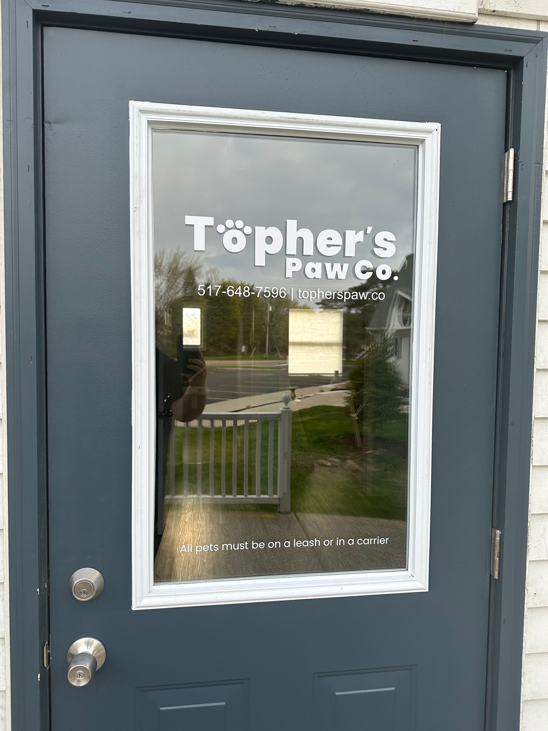 A black door with a window and the words topher 's paw co written on it.