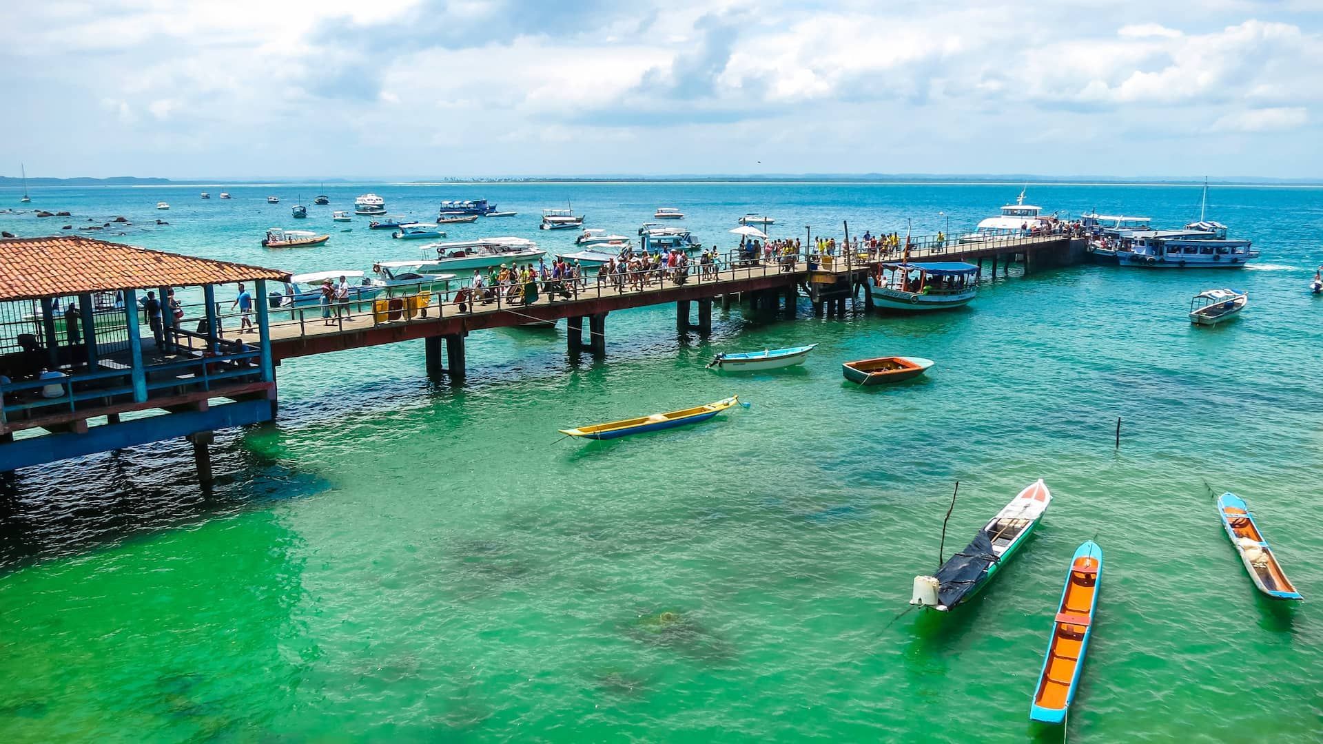 Um grupo de barcos está atracado em um píer no oceano. - Pousada Pasargada