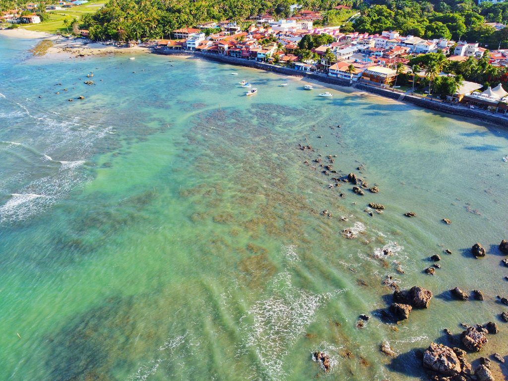 Uma vista aérea de uma pequena cidade na costa de um grande corpo de água. - Pousada Pasargada