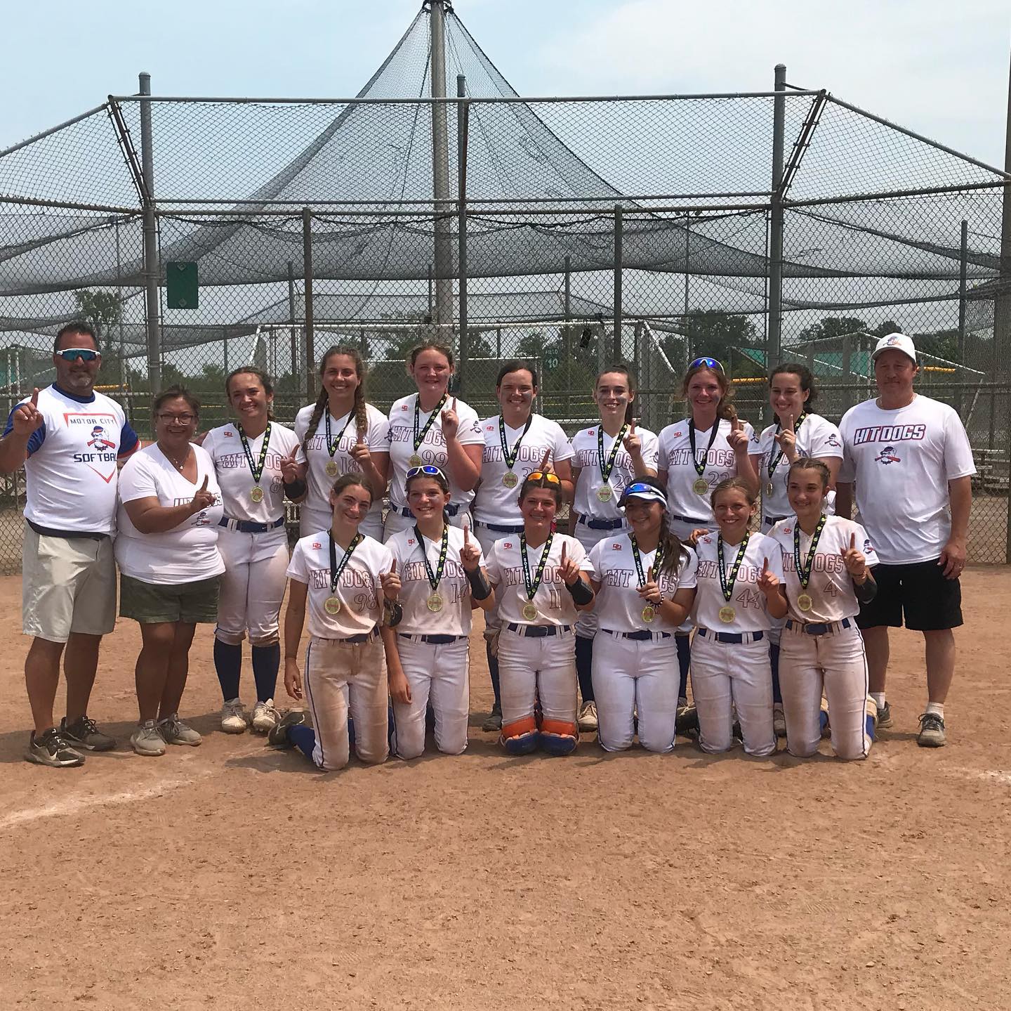 A softball team poses for a picture with their coaches