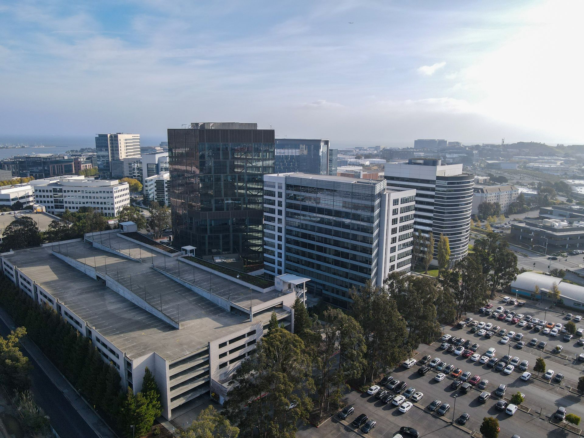 Aerial view of modern office buildings and parking lots under a blue sky.