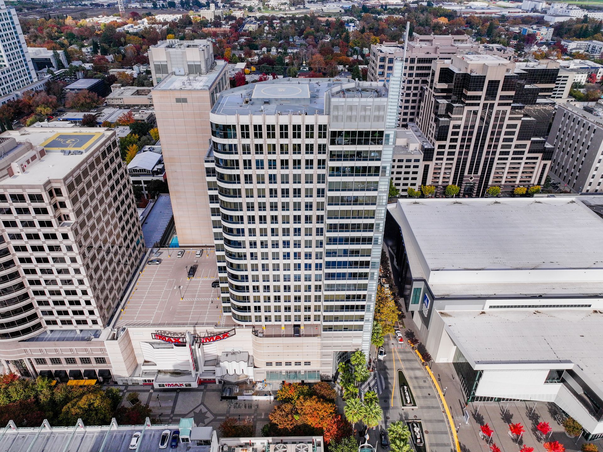 Aerial view of tall buildings in a city, including a white office tower, with a theater and event space visible.