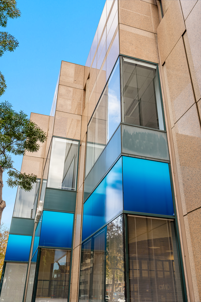 Tan building with blue-tinted windows. Tall, rectangular structure with clear and tinted glass panes.