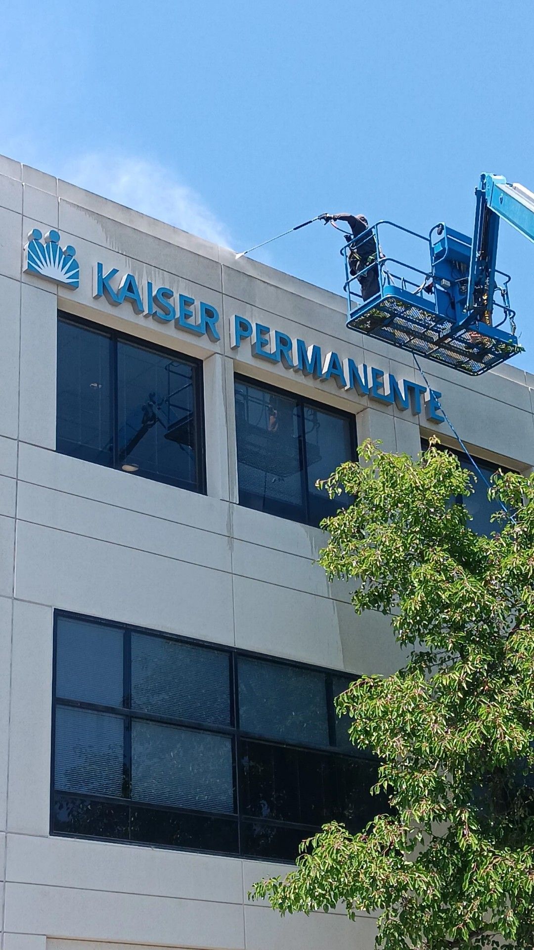 Workers in a lift installing blue letters spelling