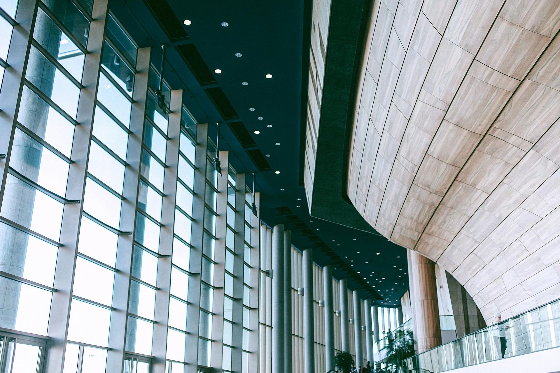 Interior of a modern building with a wall of glass windows and a curved, wooden wall.