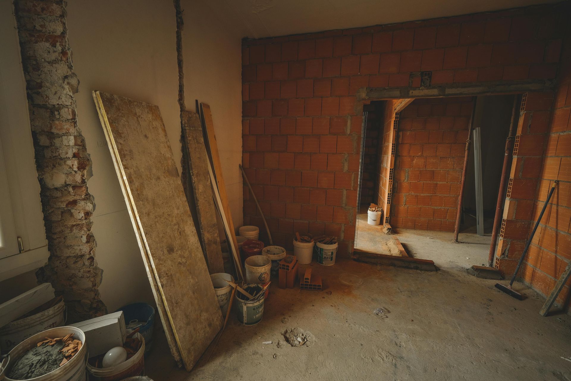 Interior room under construction, with exposed brick, drywall, and construction materials.