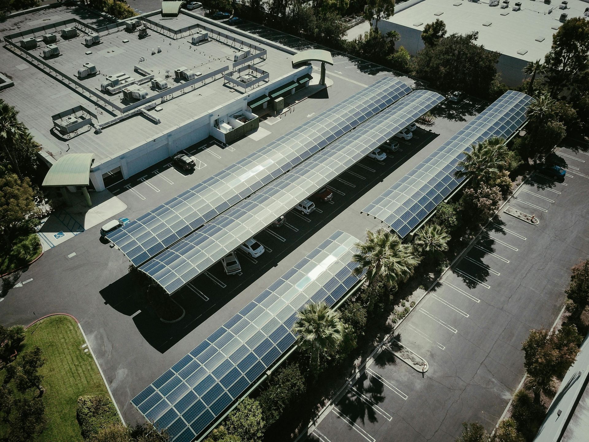 Solar panels shade parking spaces in a lot next to a building.