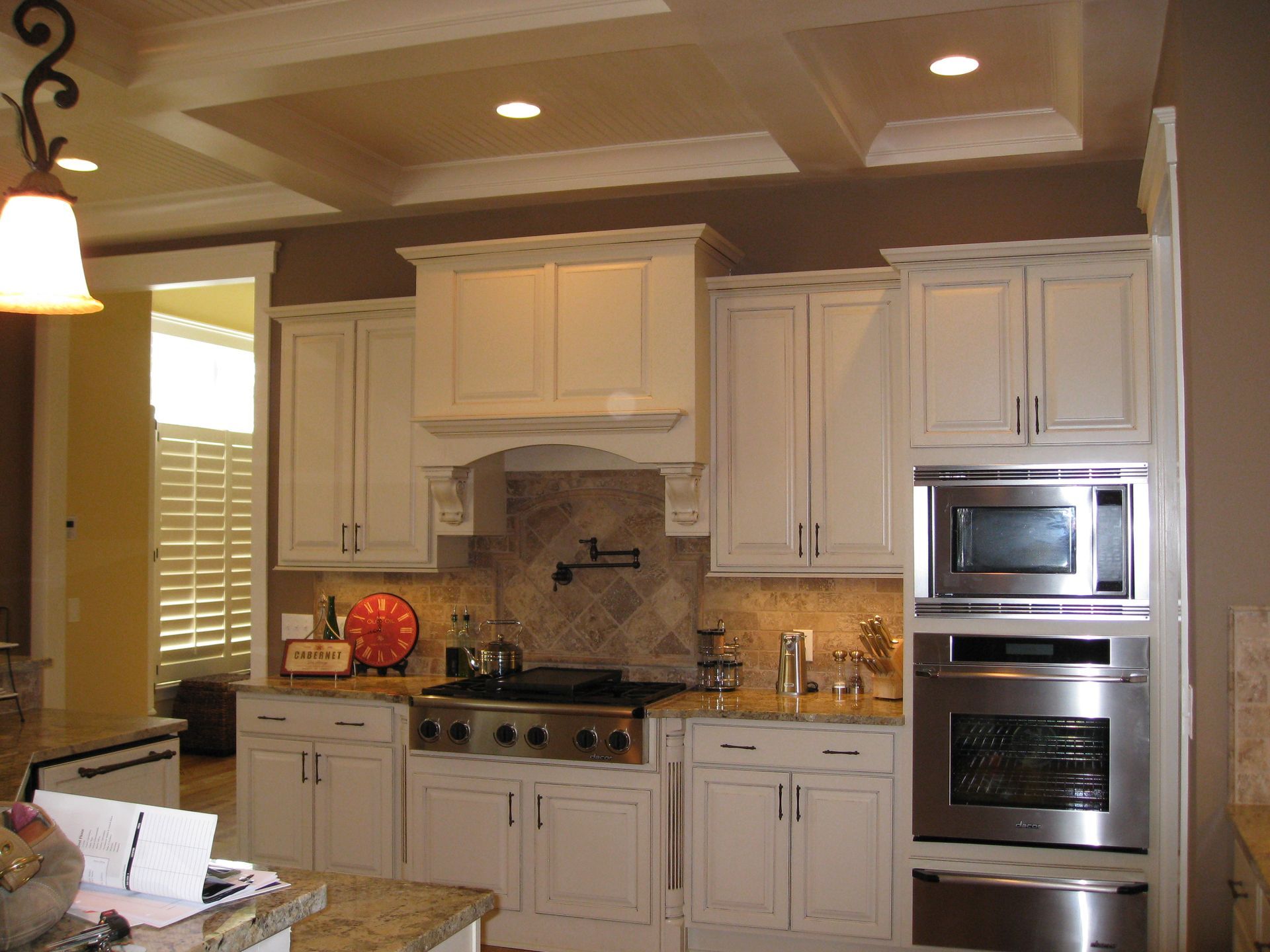 Modern kitchen with cream cabinets, stainless steel appliances, and warm recessed lighting