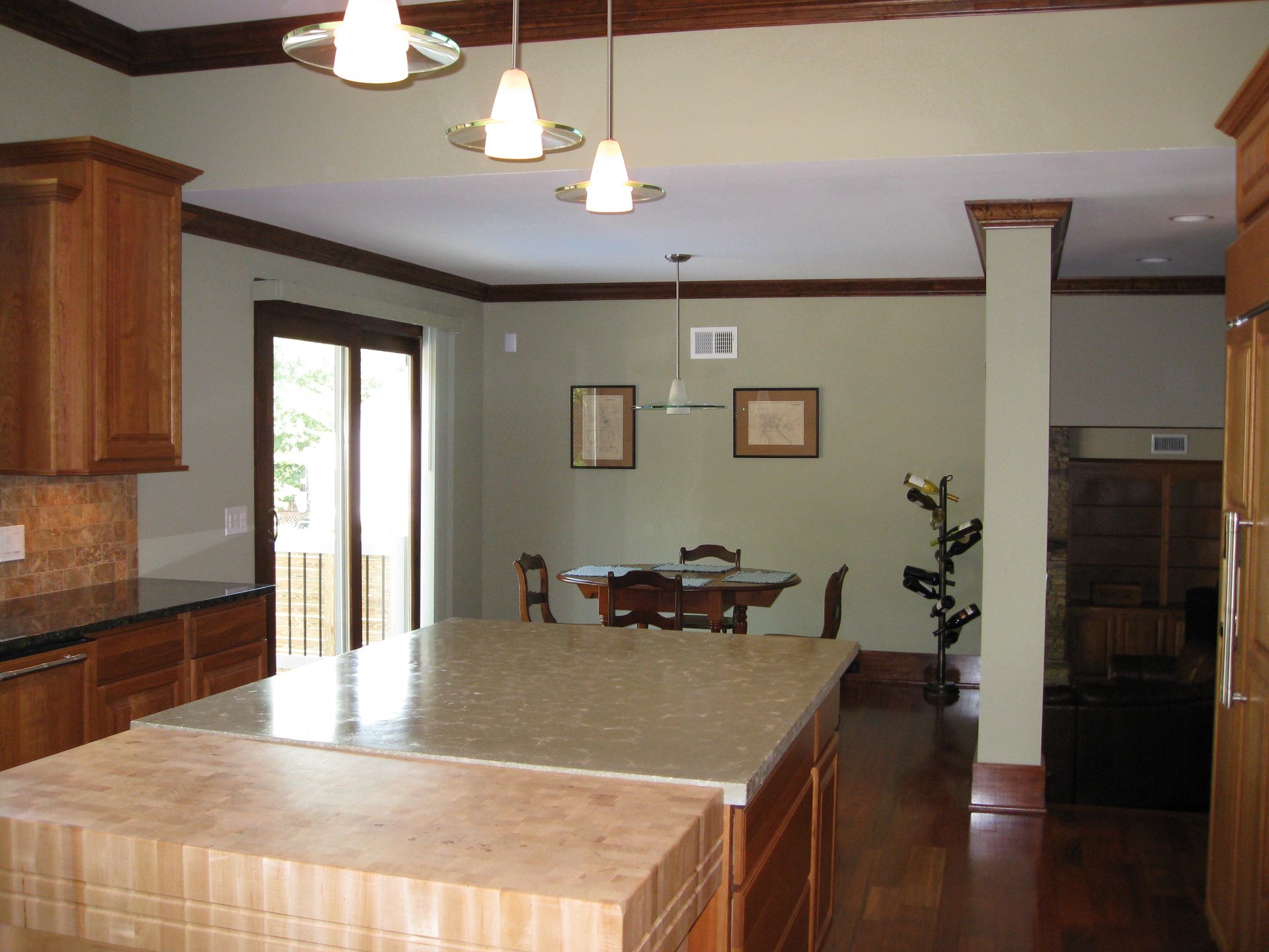 Spacious kitchen with large island, wood cabinets, pendant lights, and dining area beyond