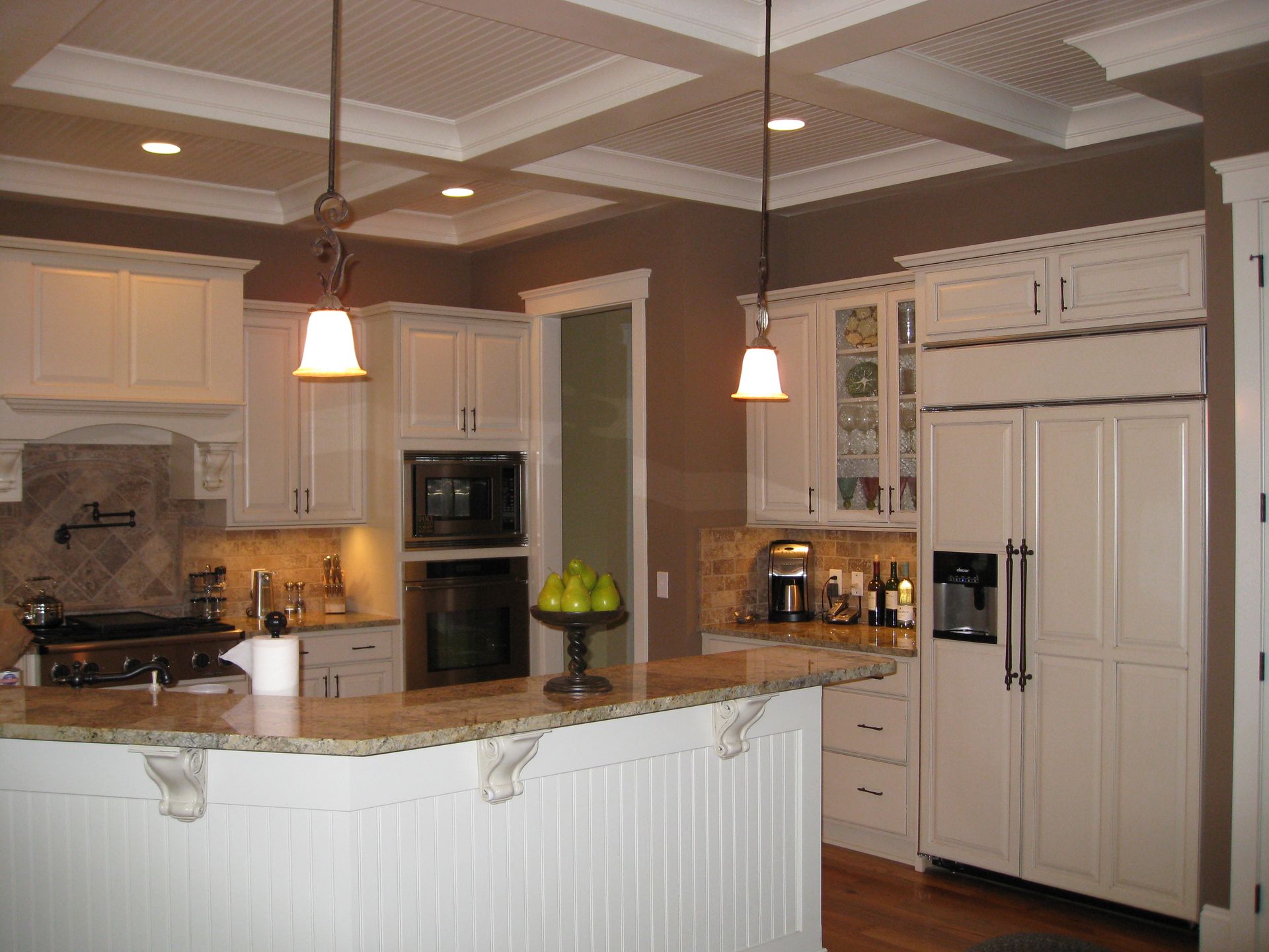 Bright kitchen with white cabinets, granite island, pendant lights, and stainless steel appliances