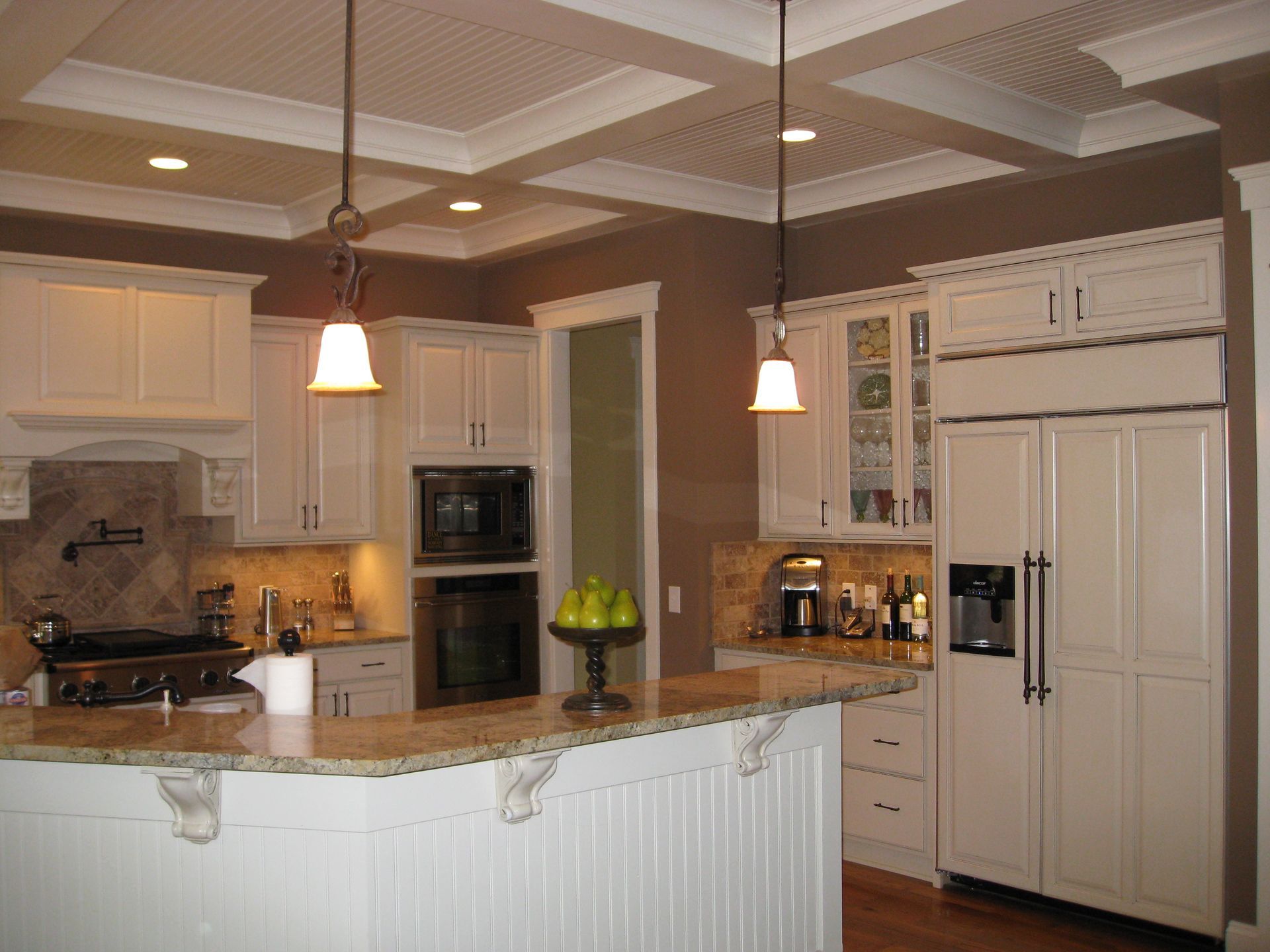 Bright kitchen with white cabinets, granite island, pendant lights, and stainless steel appliances