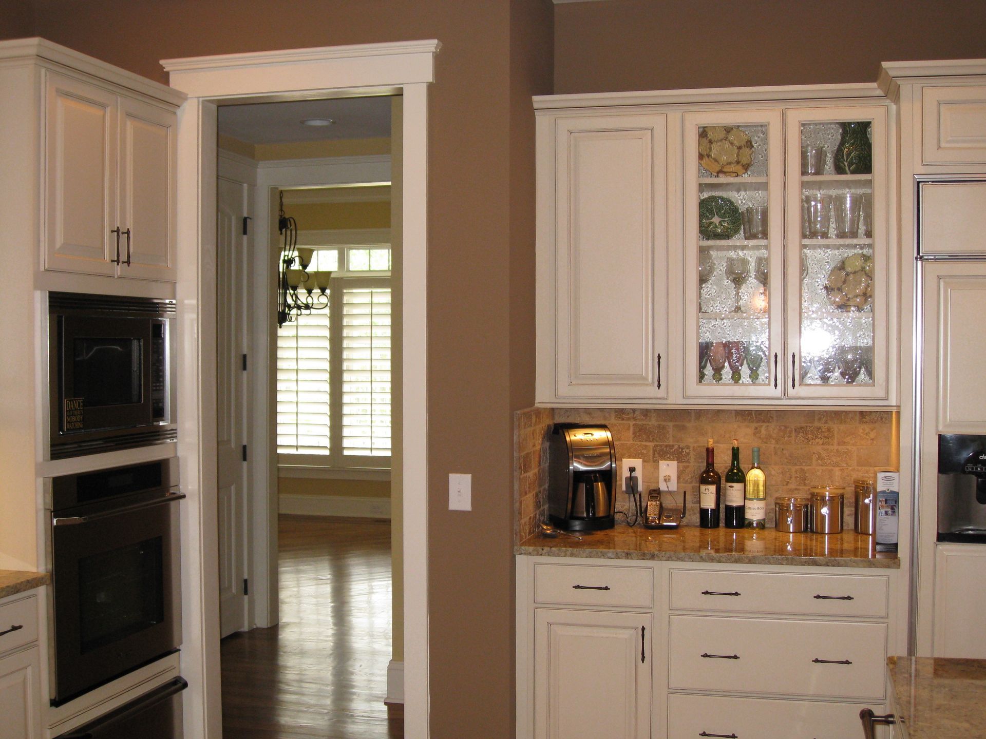 Bright kitchen with white cabinets, built-in oven, and a coffee station on the counter.