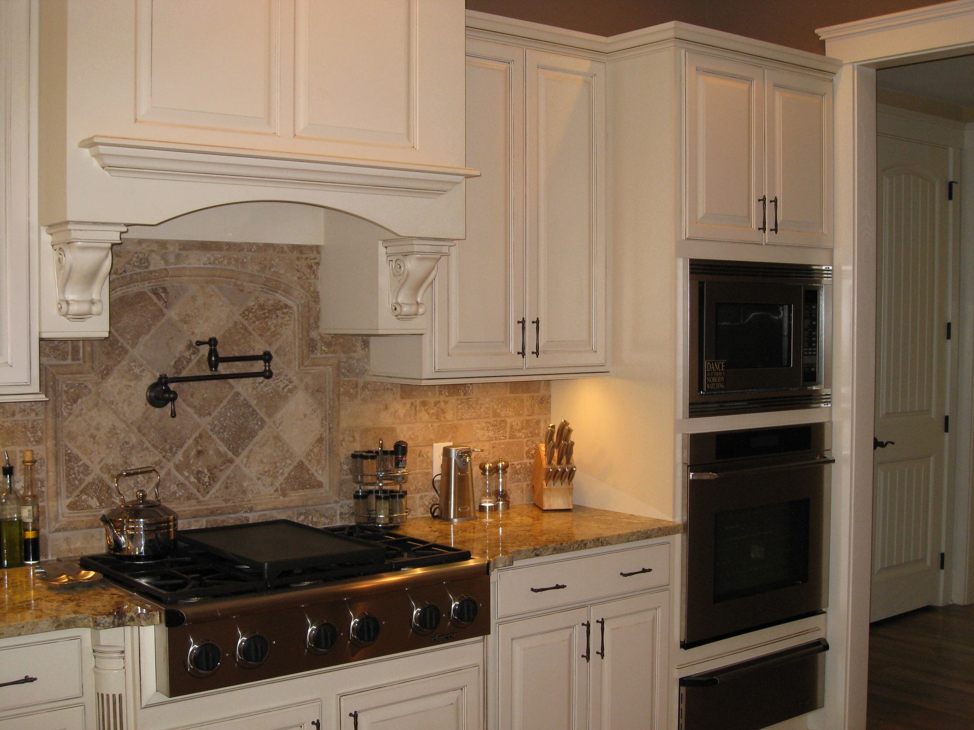 Modern kitchen with white cabinets, granite counters, black stove, and built-in double oven