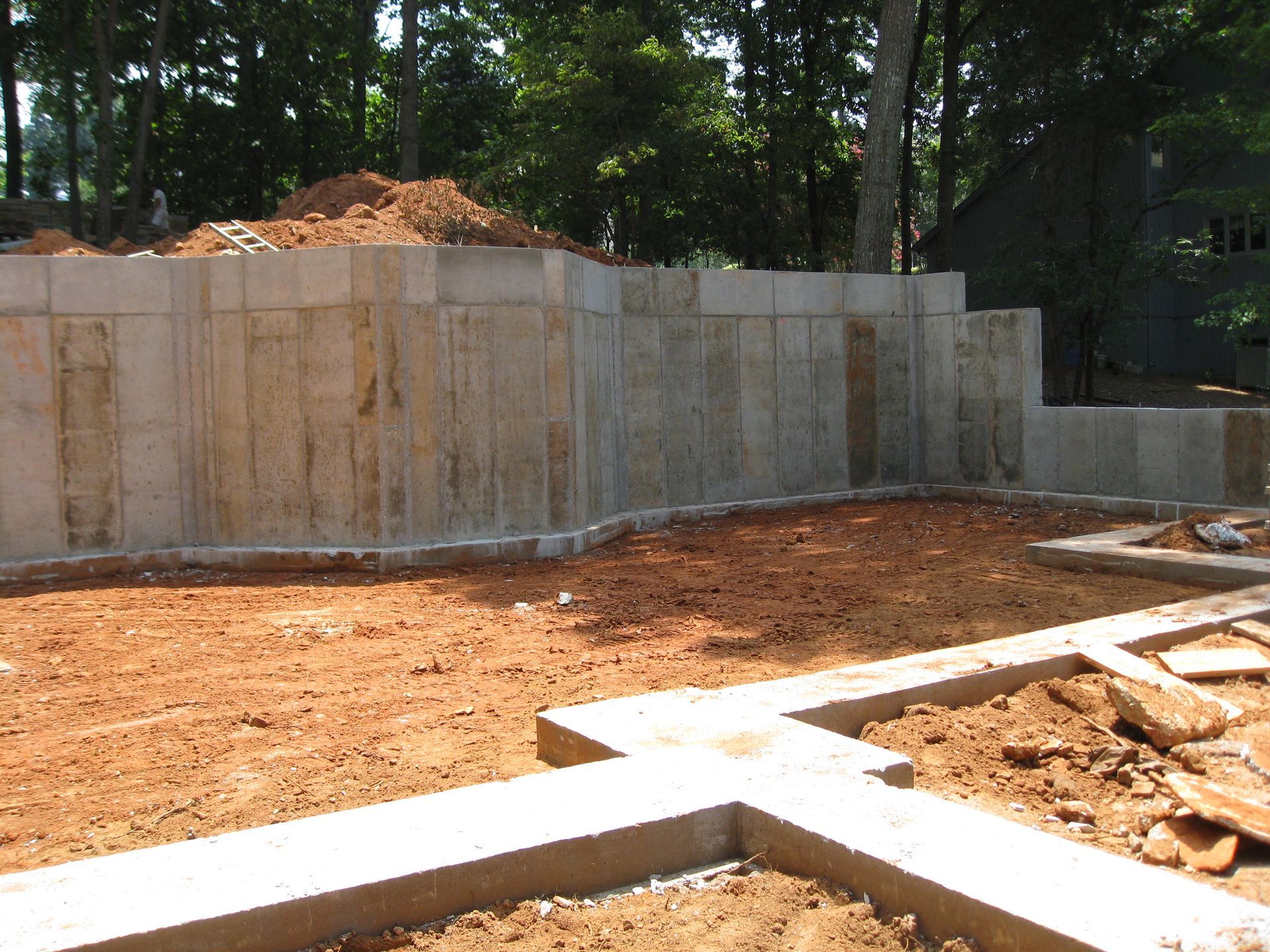 Concrete retaining wall at a construction site with dirt and wooden formwork in the foreground