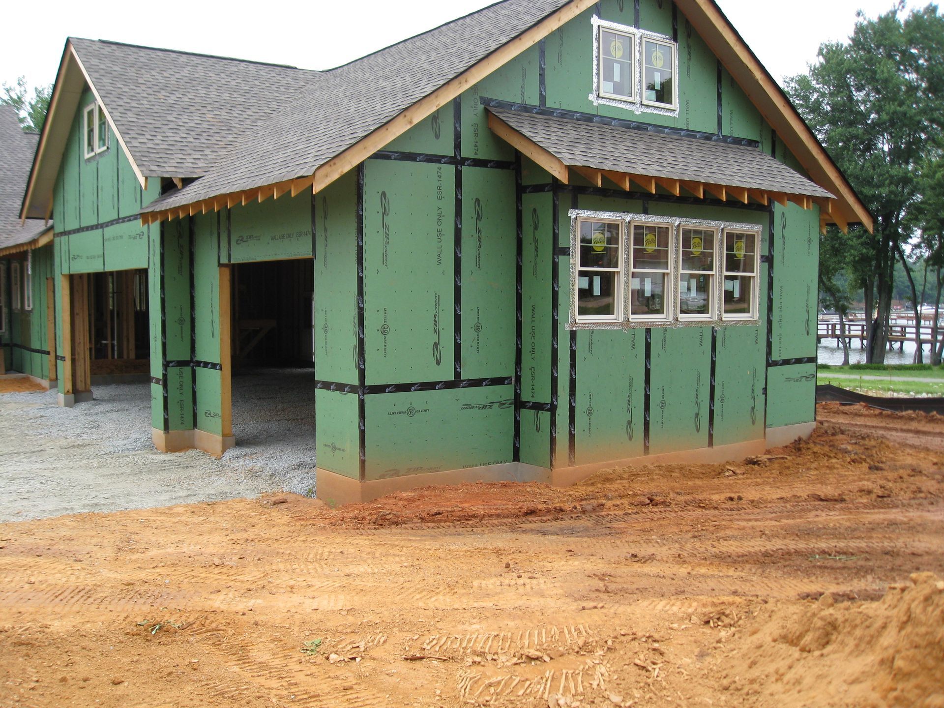 Green house under construction with unfinished siding and exposed dirt yard