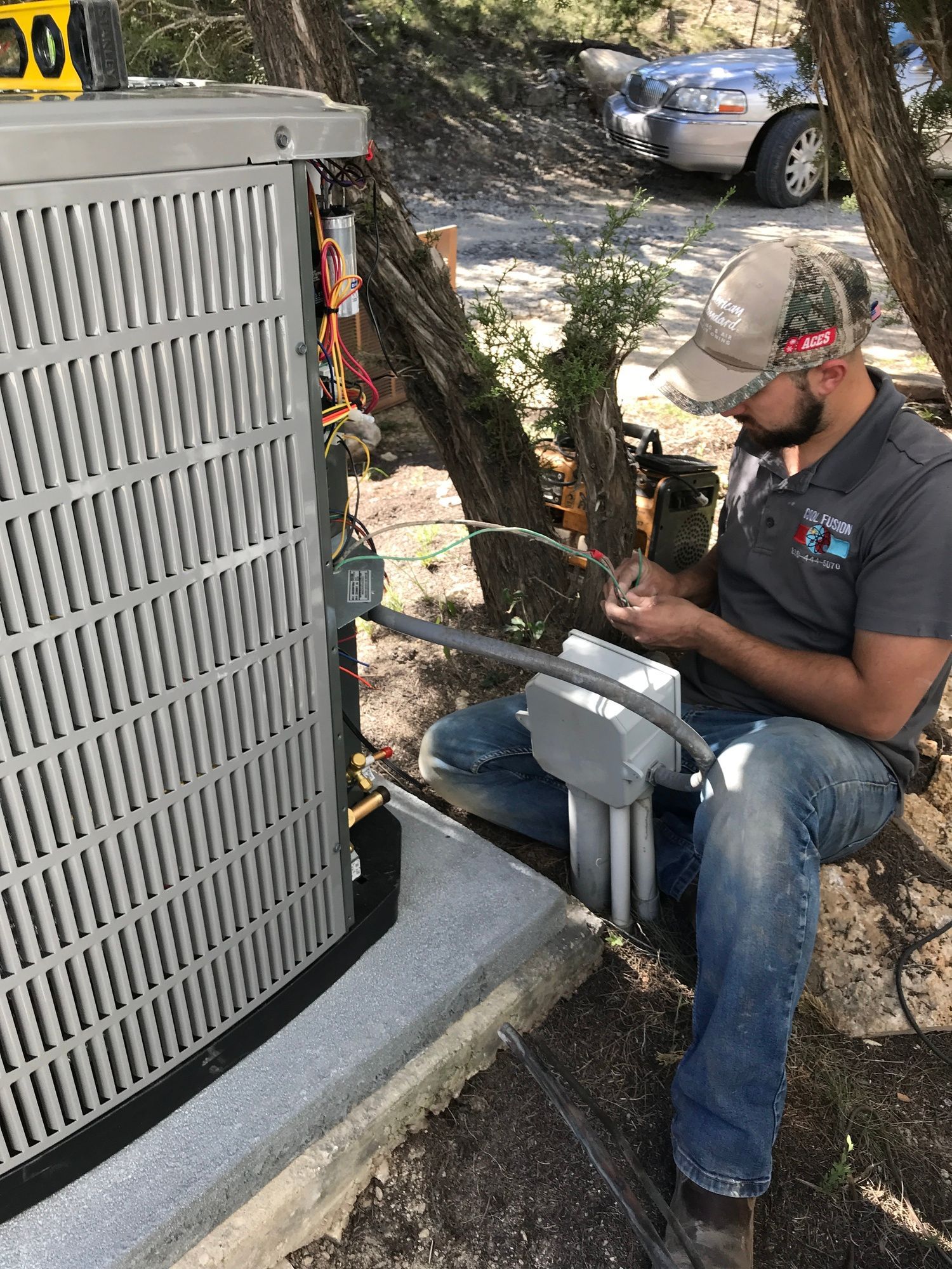 HVAC technician working on an air conditioning unit outside, connecting wires.