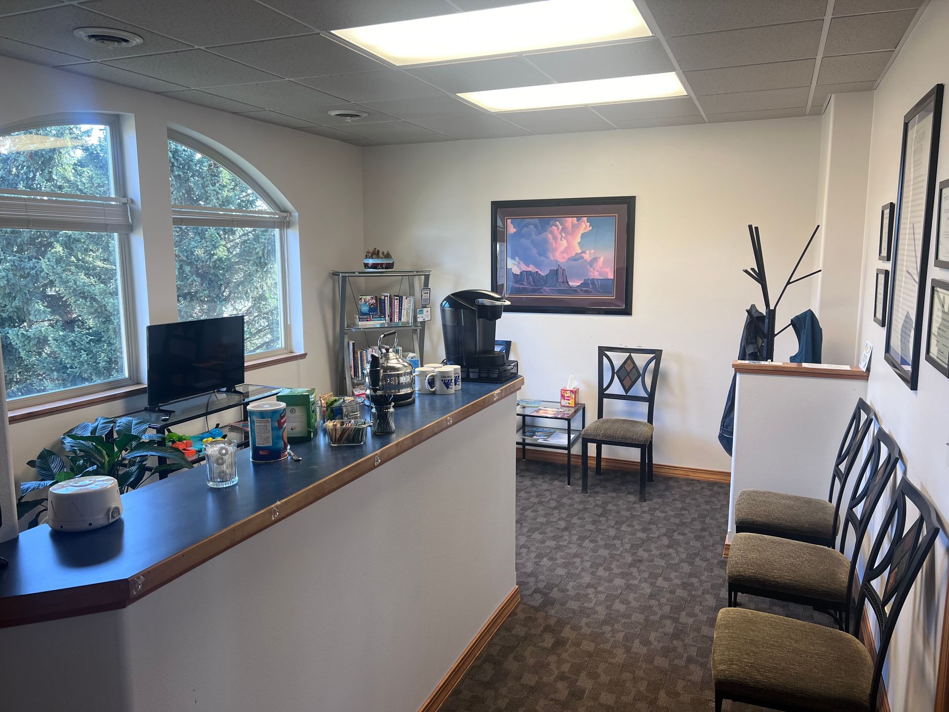 A waiting room with a counter and chairs and a picture on the wall.