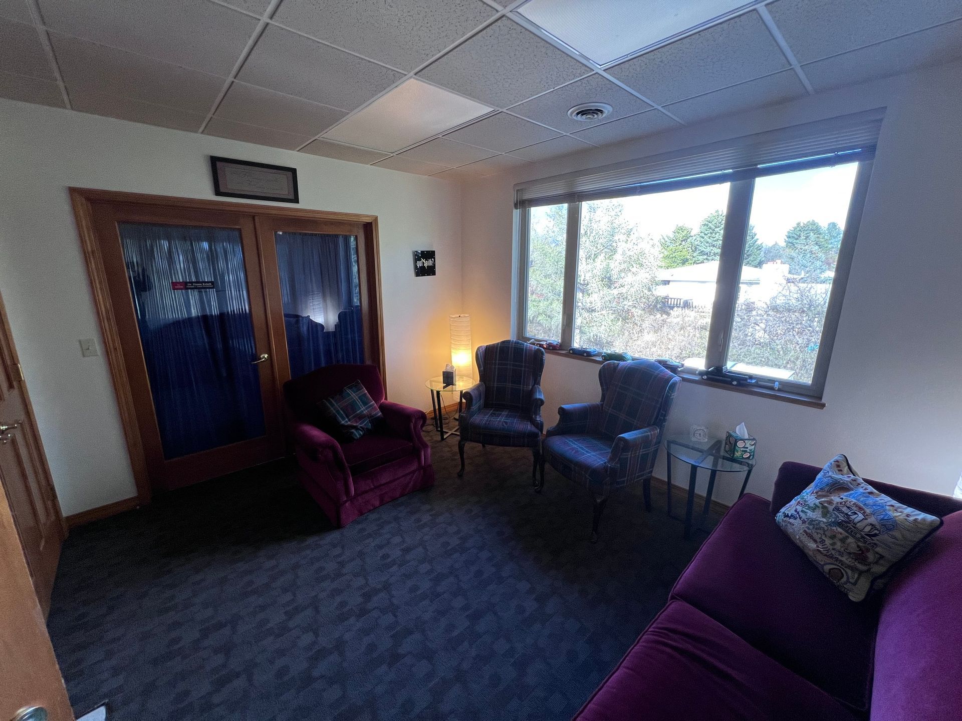A living room with a couch , chairs , and windows.