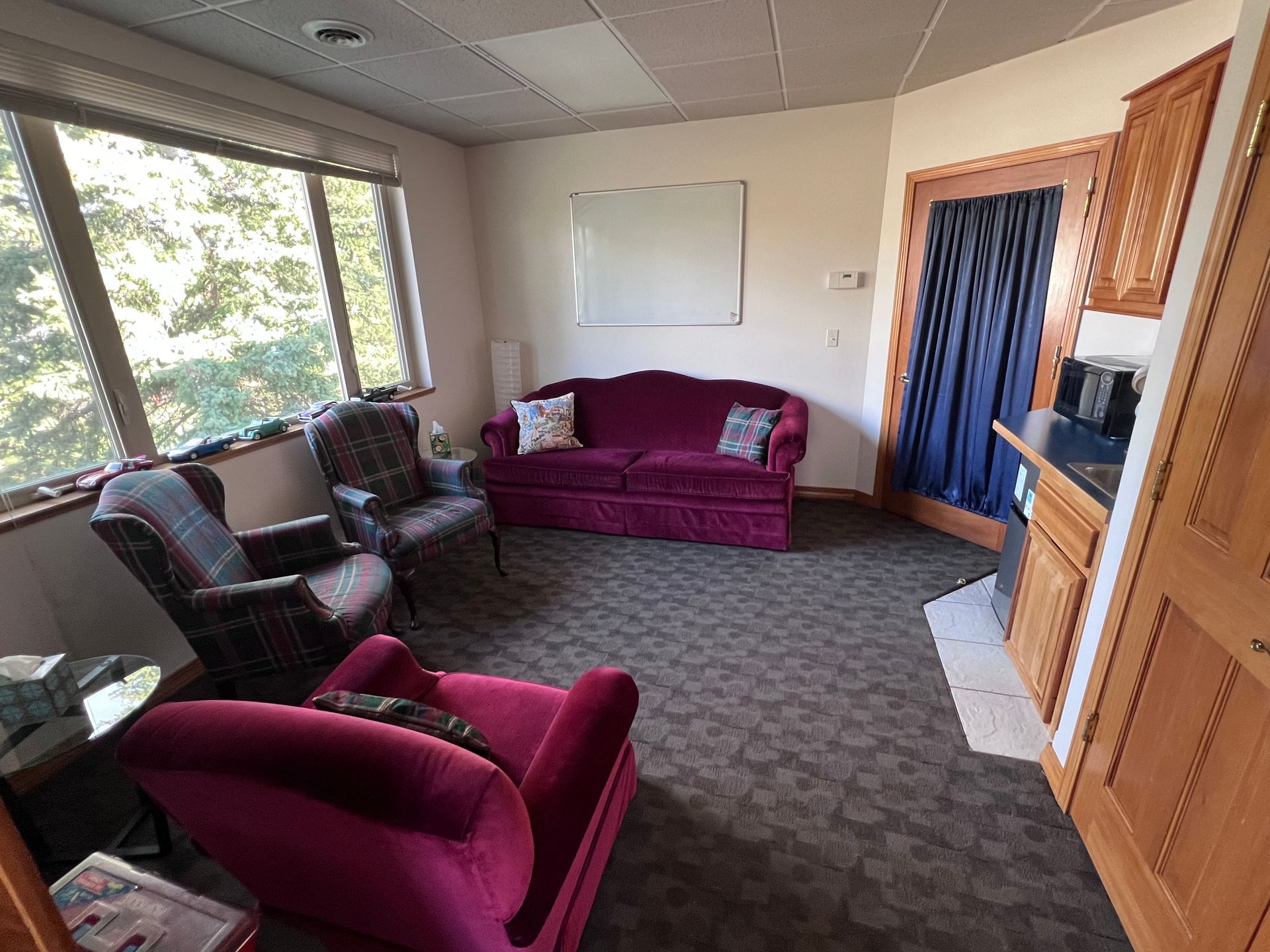 A living room with a couch , chairs , and a window.