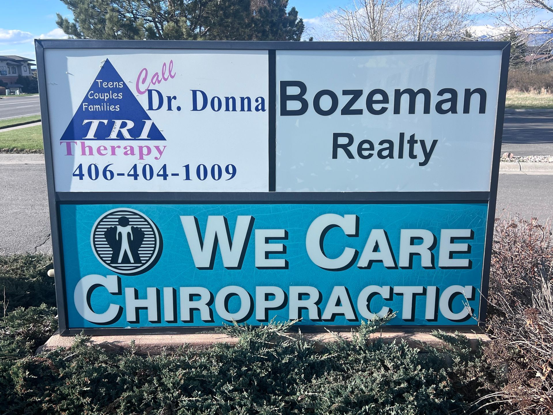 A blue and white sign that says we care chiropractic