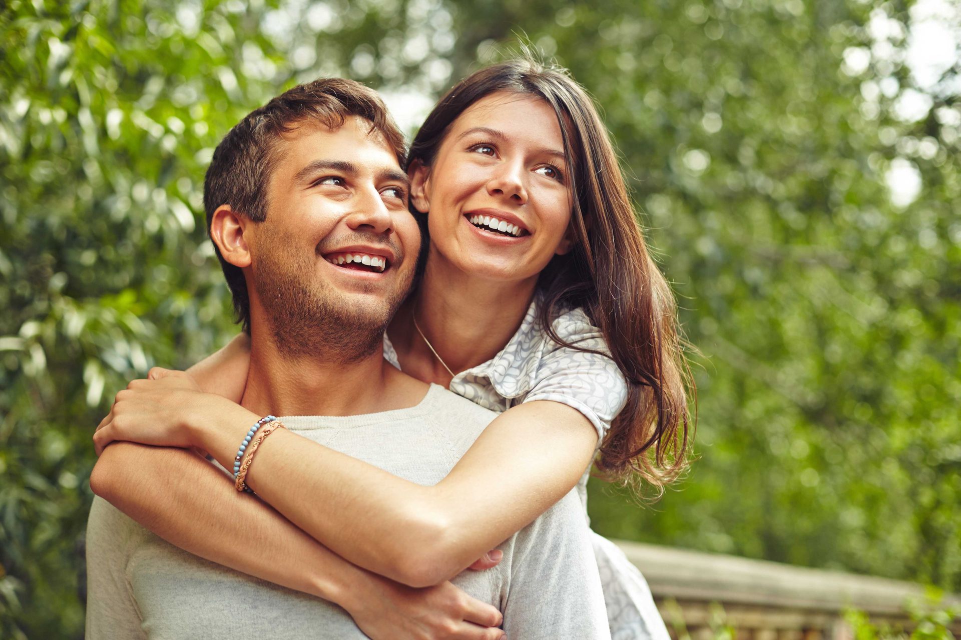 A man is carrying a woman on his back in a park