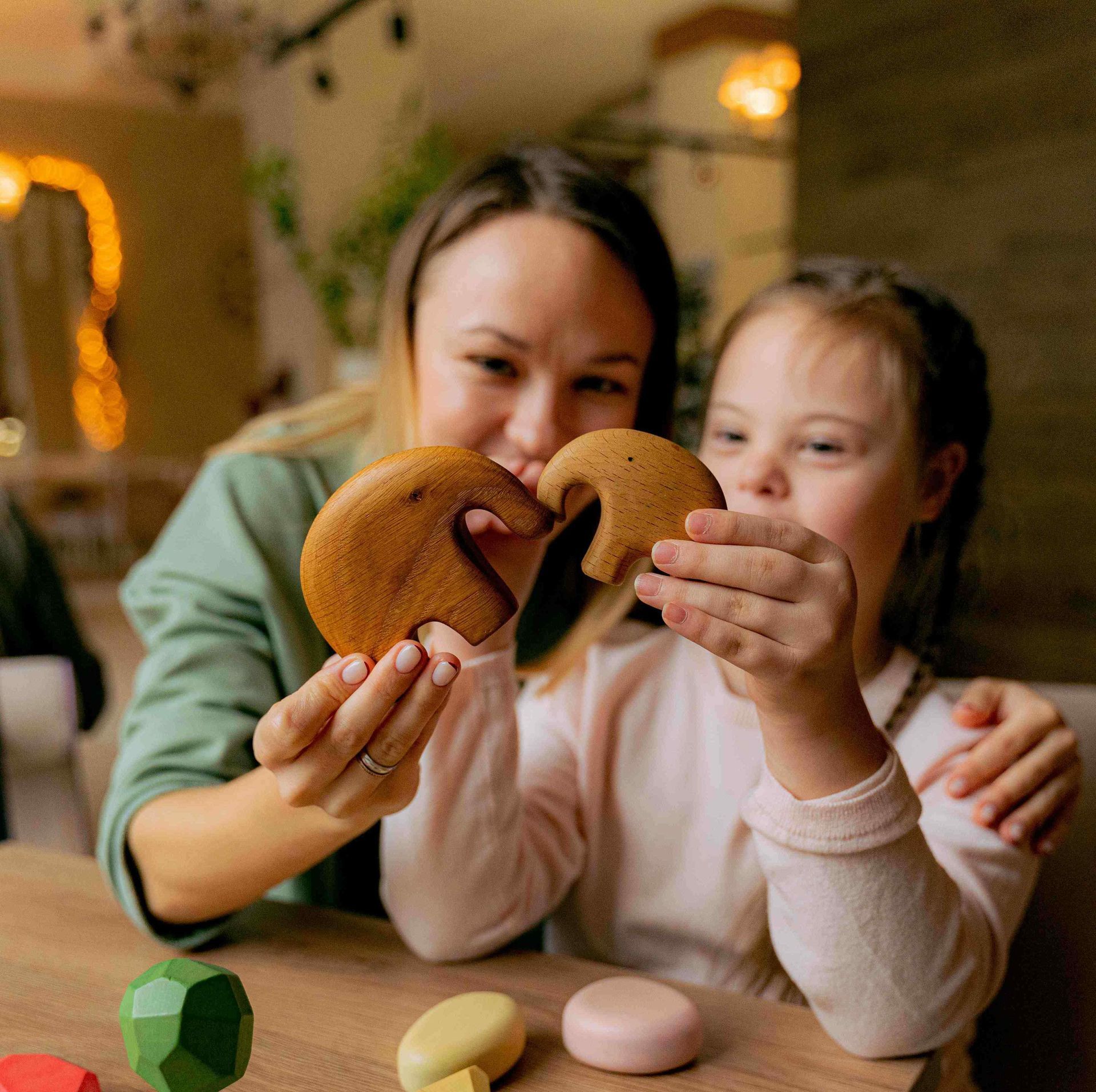 mother and her down syndrome daughter are sitting at a table and playing
