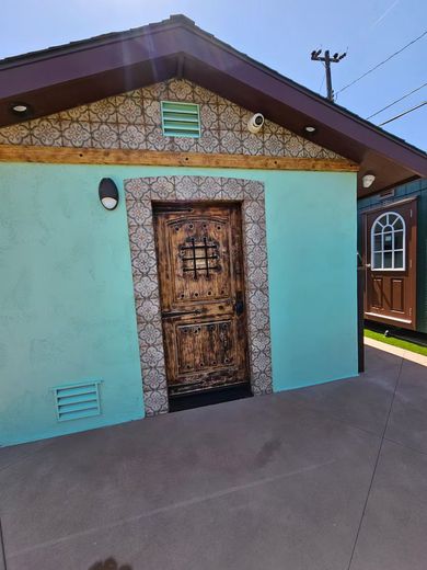 Turquoise building with ornate wooden door, stone trim, and decorative roof tile.