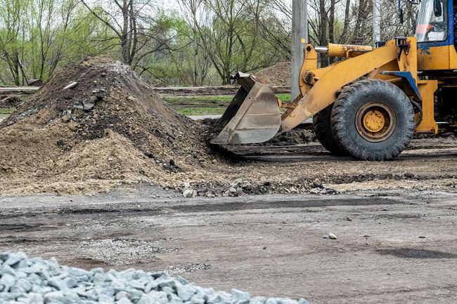 Yellow bulldozer scoops dirt from a pile on a construction site.