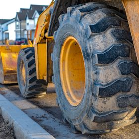 Yellow construction loader with large tires on a new paved street near houses.