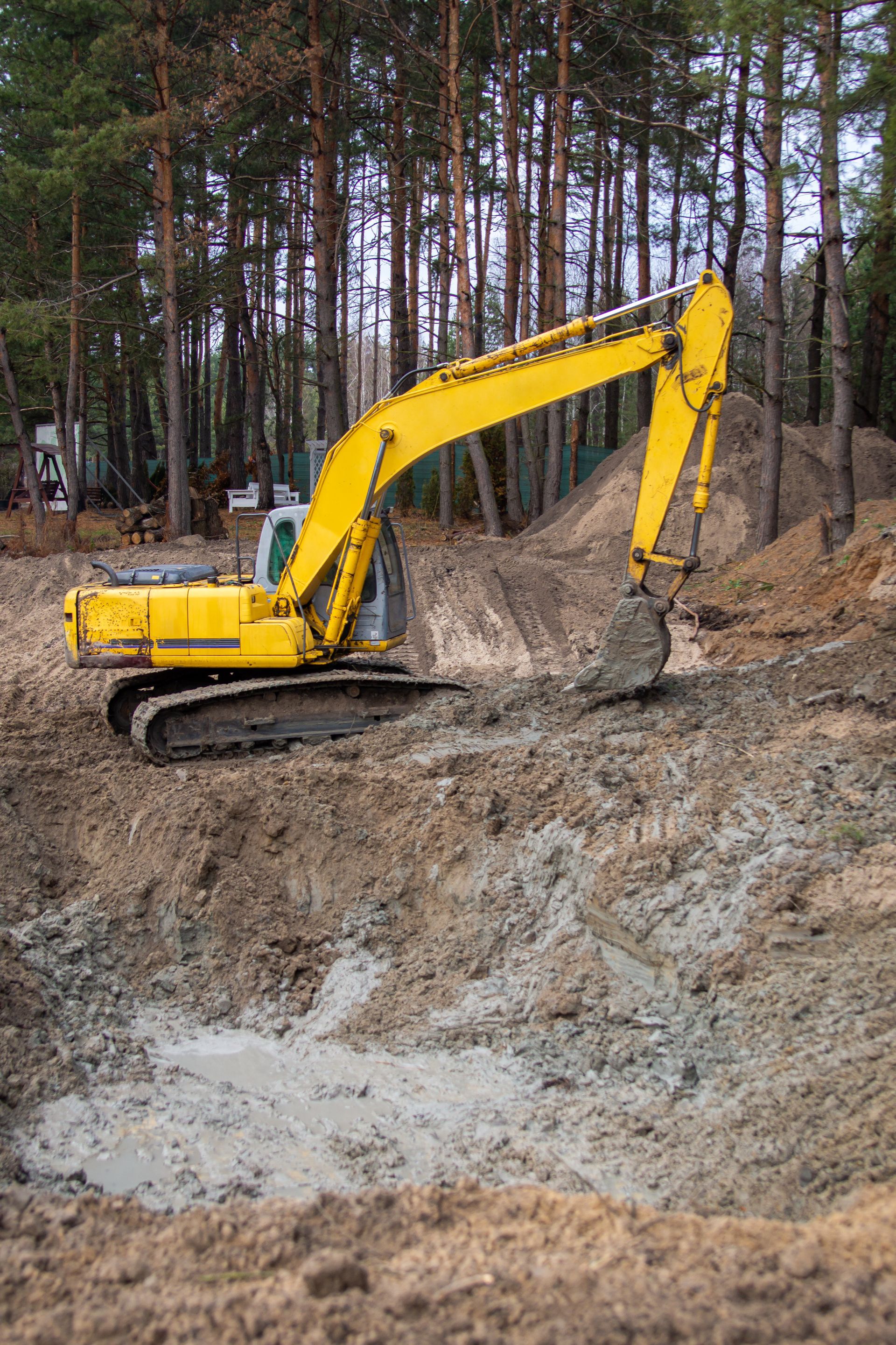 Yellow excavator digging earth at a construction site in a forest.