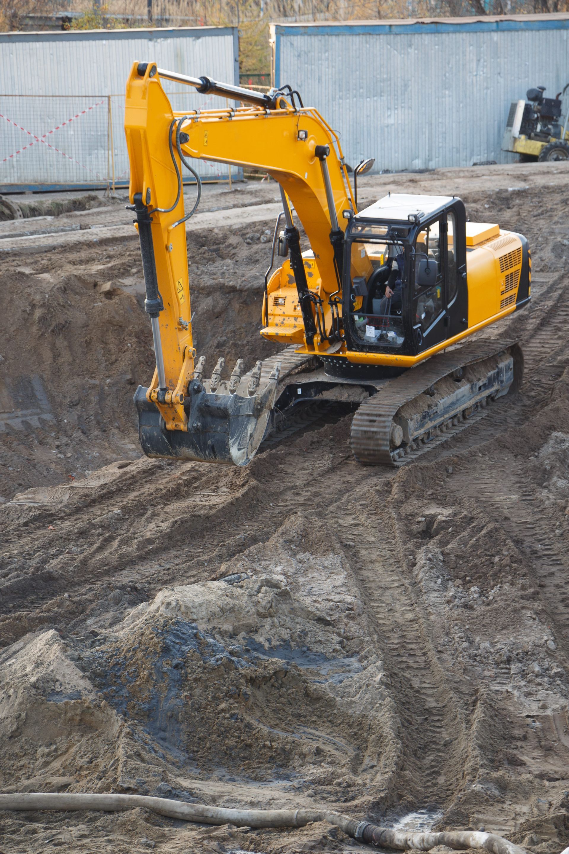 Yellow excavator digging in a dirt pit at a construction site.