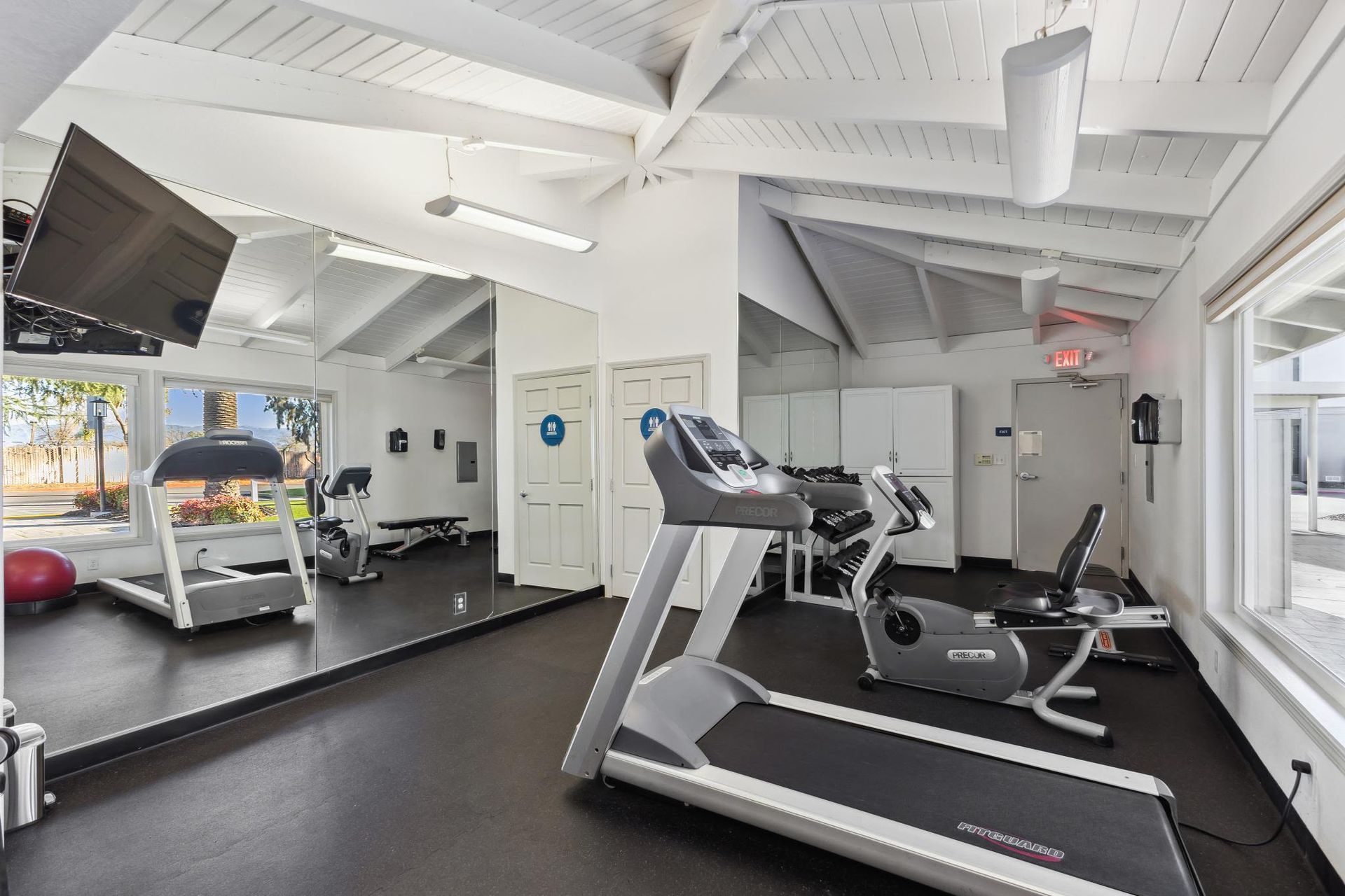 On-site fitness center with treadmill, stationary bike, mirrors and weights at Villa Palms Apartments