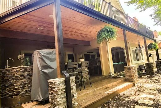 Custom Decks A large covered porch with a grill on it and a stone wall.