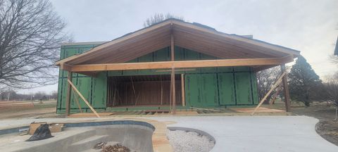 Accessory Dwelling Unit Construction of a building with a large wooden roof supported by beams and props. The exterior has green sheathing.