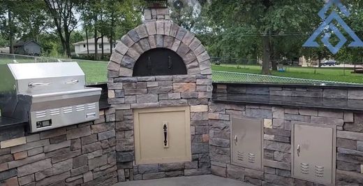 Pizza Oven A pizza oven is built into a stone wall next to a grill.