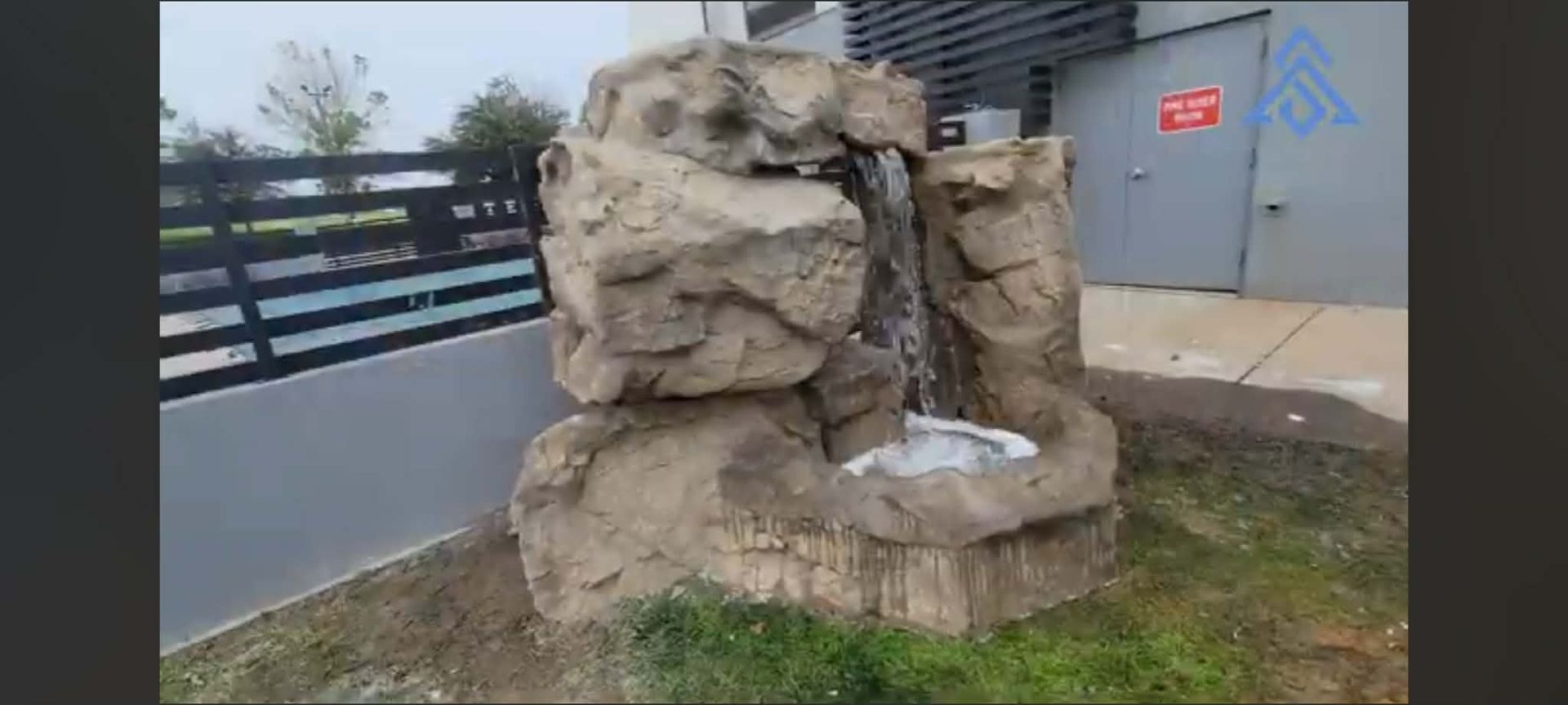 Custom 6x6 artificial rock waterfall built by Scapesart beside a commercial building in the Kansas C