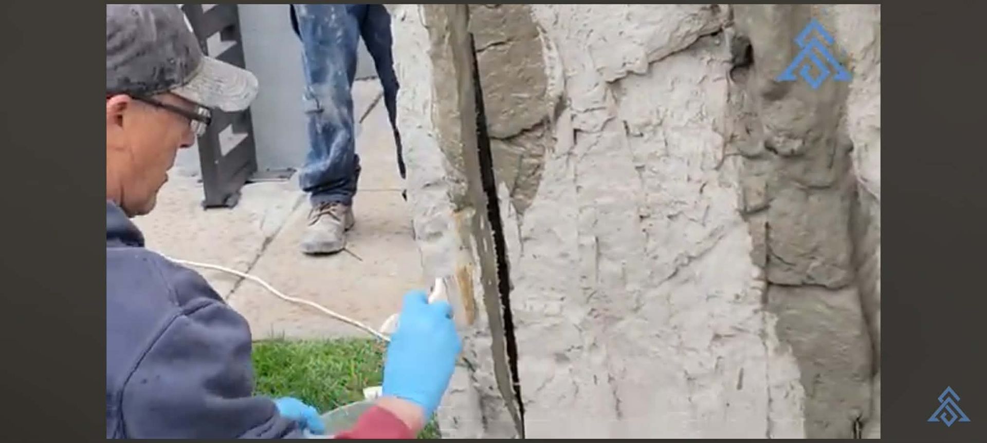 Worker in blue gloves inspecting a cracked concrete wall with a probe at a construction site
