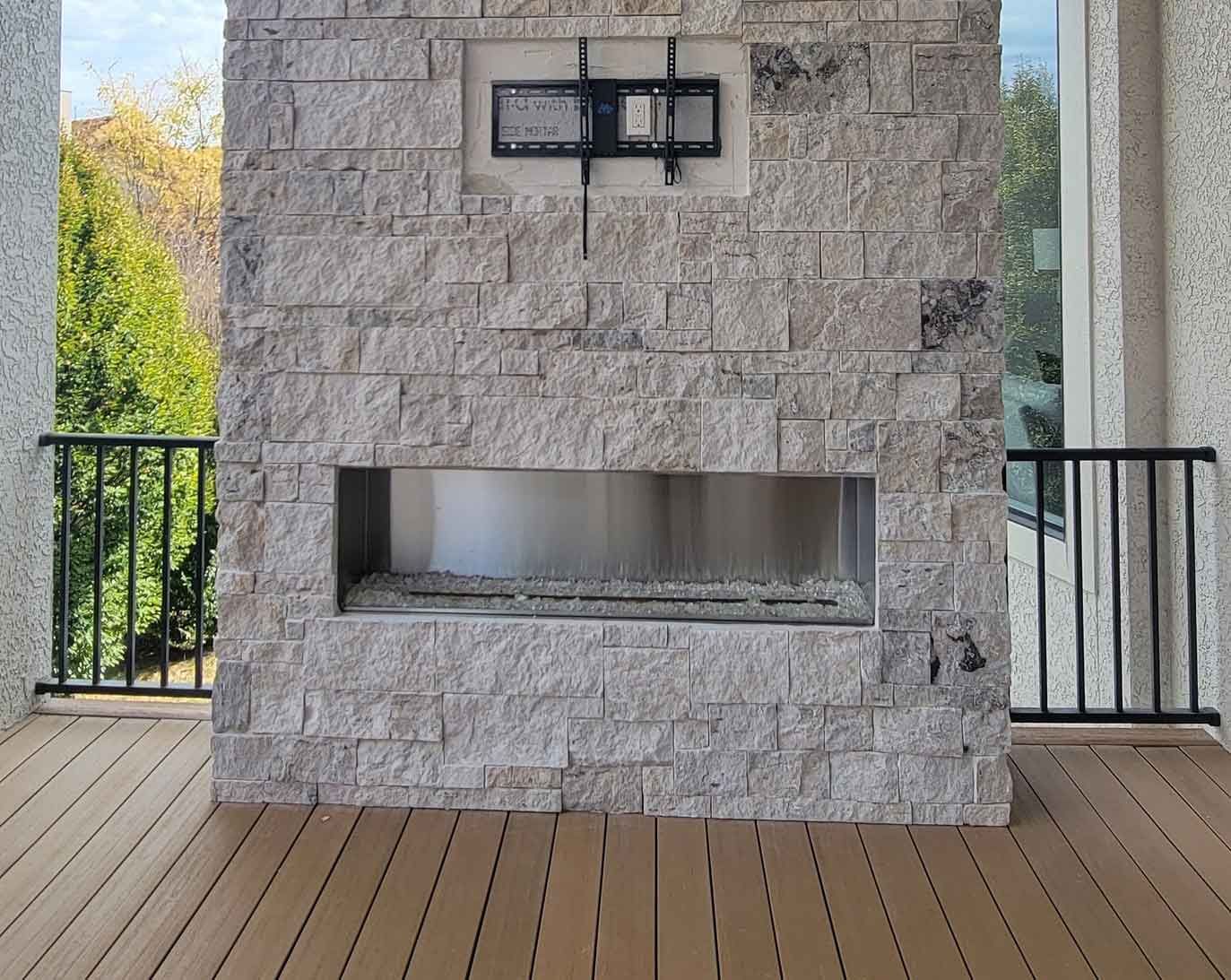 Outdoor Fireplace FAQ: 10 Essential Questions Answered. A fireplace is built into a stone wall on a deck.