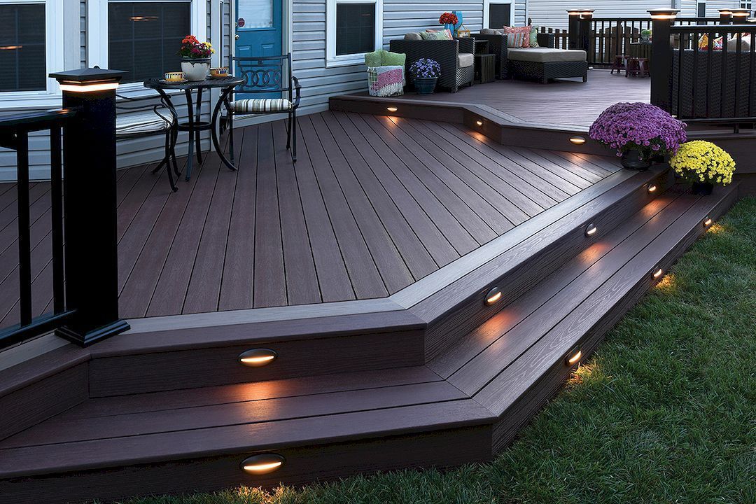 A wooden deck with stairs leading up to it is lit up at night.