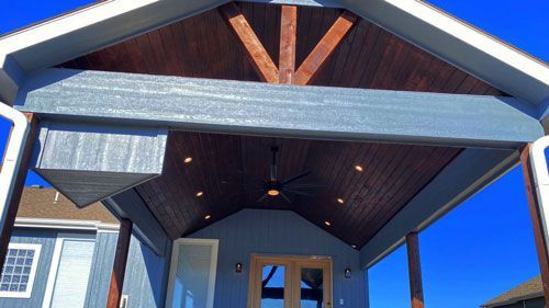 Custom Porch FAQ for KC: Your Top 10 Questions Answered A blue house with a porch and a ceiling fan
