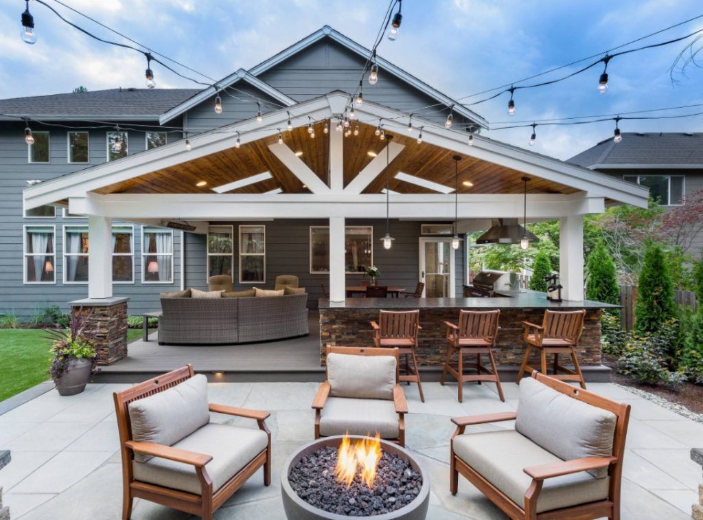 A patio with chairs and a fire pit in front of a house.
