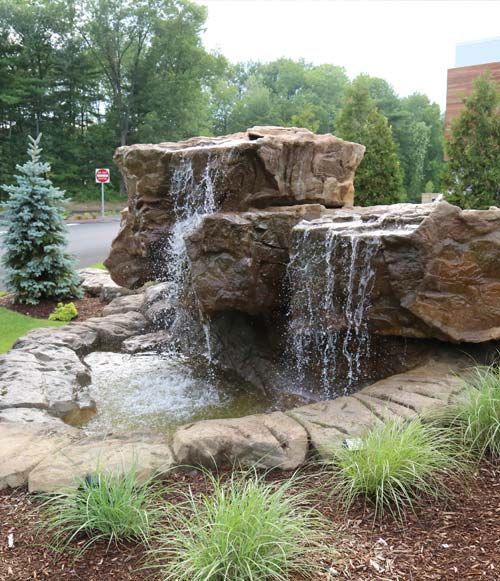Artificial Rock Water Fall A waterfall is surrounded by rocks and trees in a park.