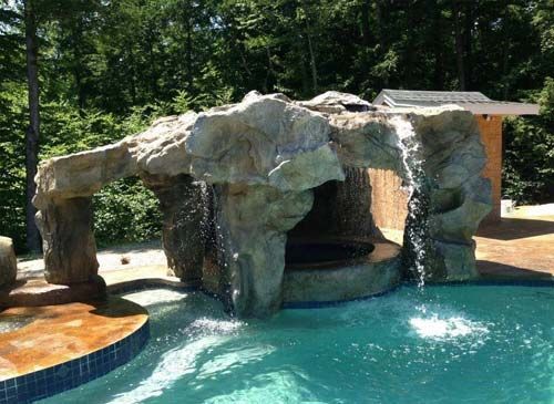 Artificial Rock Grotto FAQ for KC Homeowners: Top 10 Questions Answered There is a waterfall in the middle of a swimming pool.