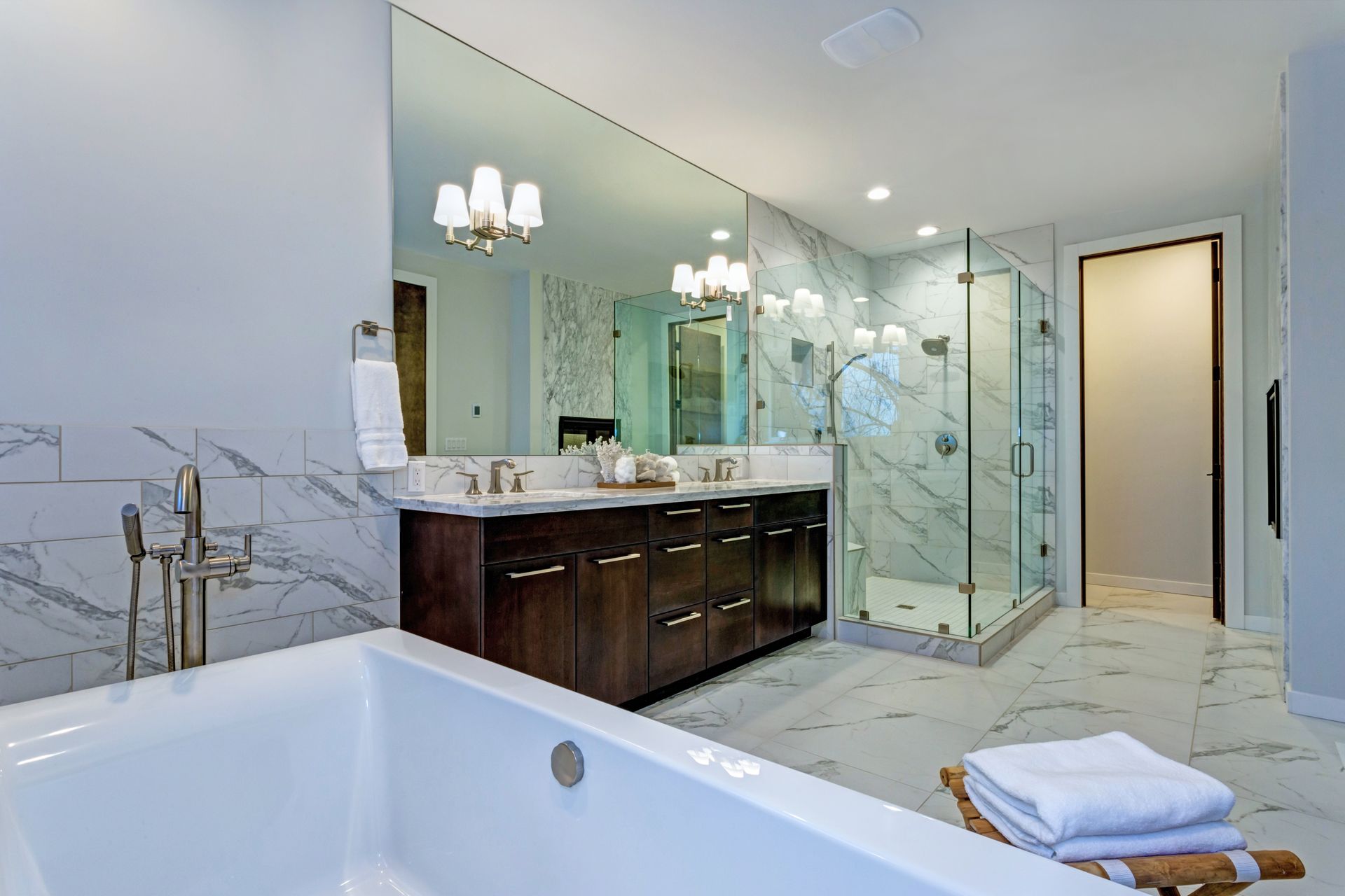 Spacious marble bathroom with custom glass shower mirrors above a double vanity
