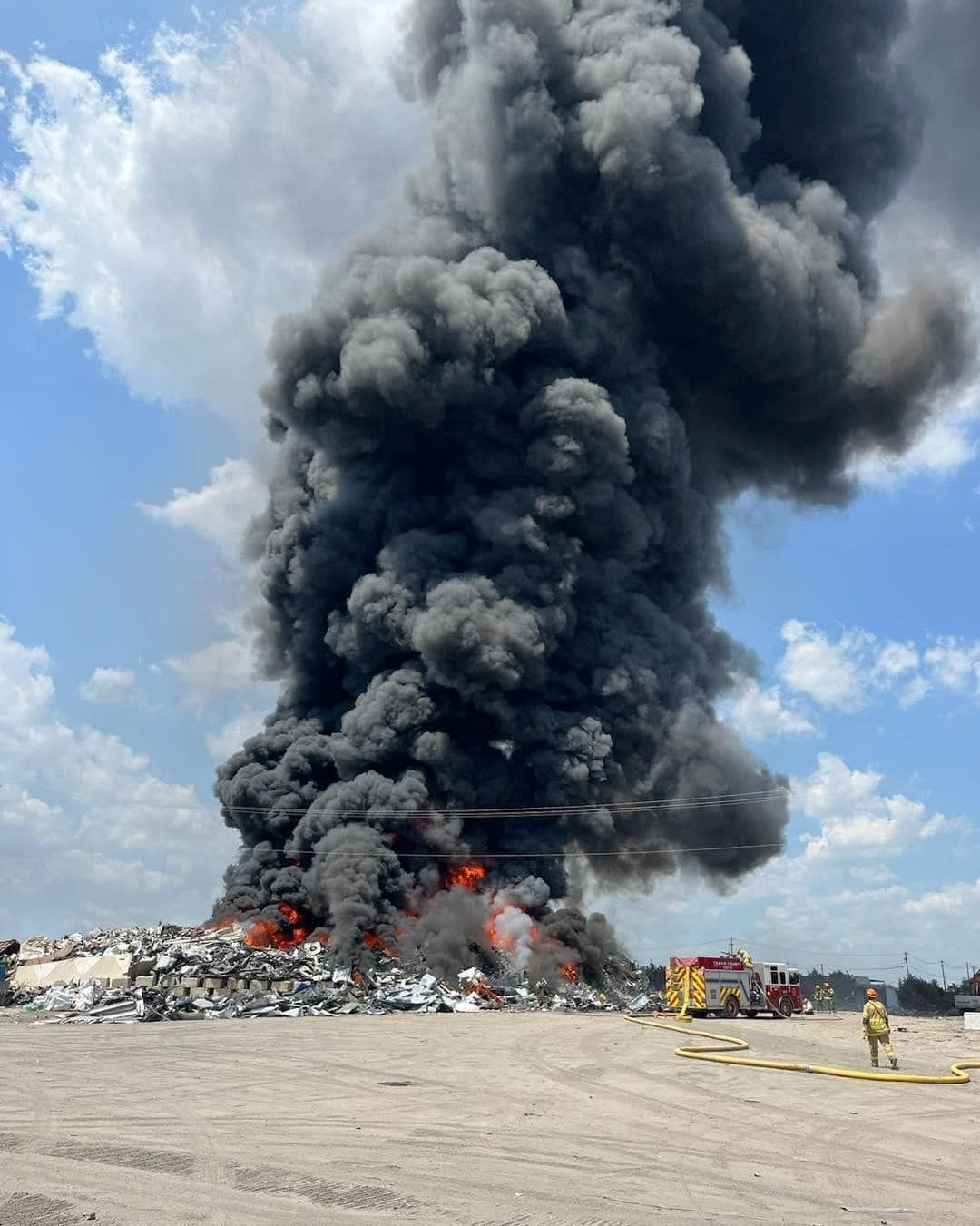 A large cloud of smoke is coming out of a fire in a field.
