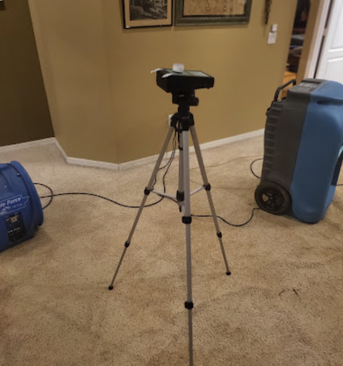 A camera on a tripod next to a blue vacuum cleaner